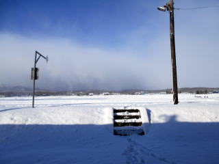 下徳富のホームへ上る階段。雪に覆われているが、ホームの先には田園風景が広がる。
