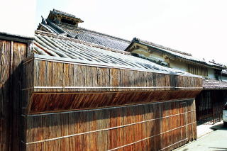 母屋外観、瓦屋根の補修を行うために杉皮での防護柵が設けられている。