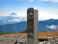 山頂標識と中腹に雲がかかる富士山