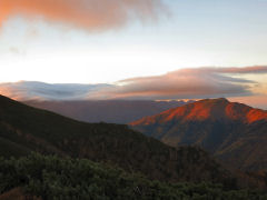 南側には朝日が当たる山、上部が雲に包まれた山が見える