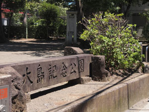 写真2　大島記念公園の表示された石柱の奥に震災記念碑がある