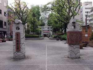 写真2　塩釜公園の門柱　右側に「塩釜公園の沿革」と題した花崗岩の石盤（説明板）がある　中央奥に鹽竈神社の鳥居が見える