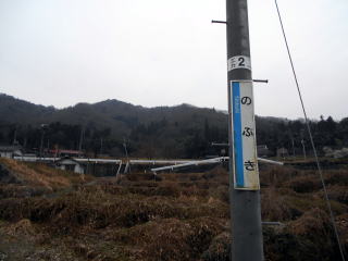 信木の駅名板と、河岸段丘の上段にある集落