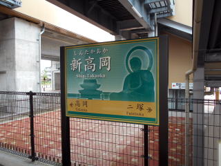 新高岡の駅名標。高岡のシンボルとなっている高岡大仏のシルエットが描かれたデザインだ。